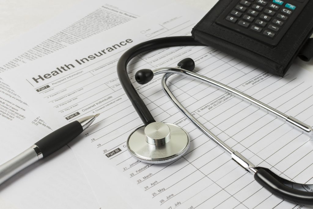 Stethoscope, calculator, and pen resting on insurance form.